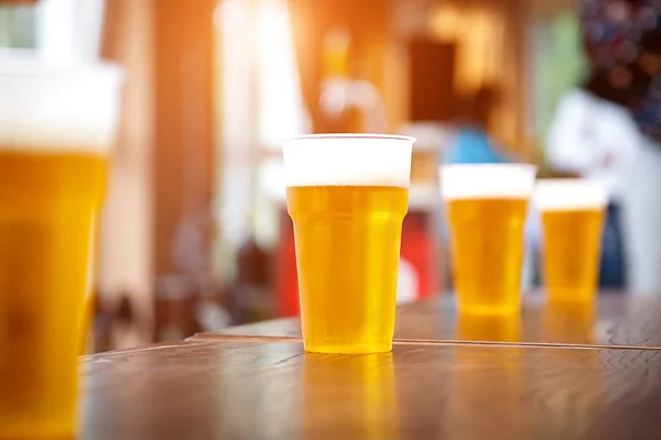 Uma fileira de copos de cerveja de plástico com uma cerveja light — Fotografia de Stock