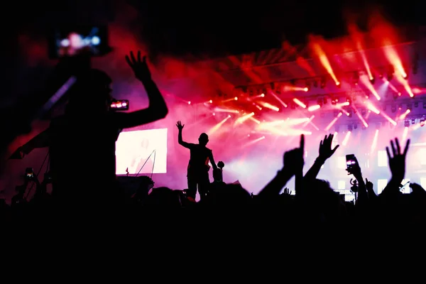 Silhuetas de mãos em concerto na frente de luzes do palco brilhante — Fotografia de Stock