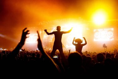 Konser kişi kalabalığın içinde omuzlarında ile el kadar bir müzik festivali - arkadan aydınlatmalı aydınlatma ile siluet.