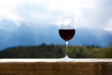 Güzel dağ arka plan önünde ahşap bir masa üzerinde bir piknik duran, kırmızı şarap cam