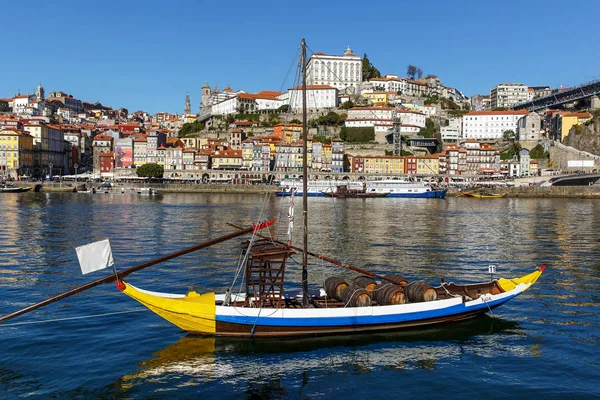 Traditionele houten boten aan de Dourorivier voor het vervoer van wijn met de stad op de achtergrond van de stad Porto, Portugal. — Stockfoto