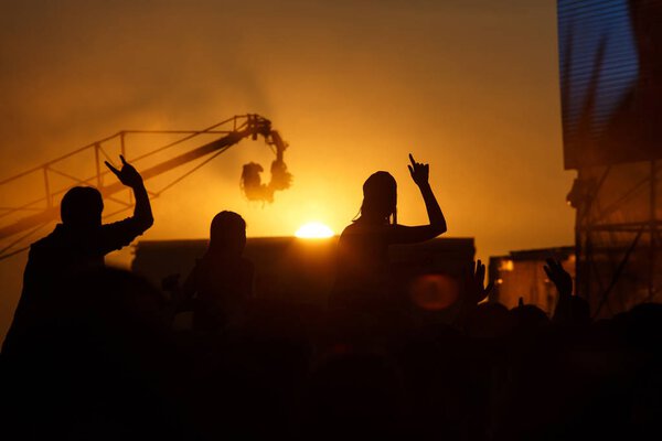Silhouette of people in sunset on holiday. summer lifestyle. Colorful warm orange toning. Pleasure at the Summer Music Festival. TV crane above the crowd