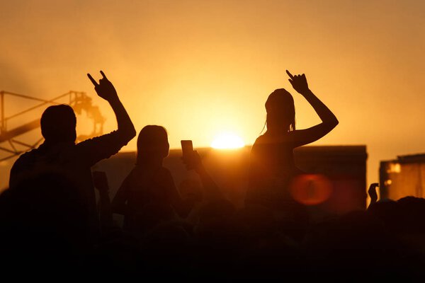 Silhouette of people in sunset on holiday. summer lifestyle. Colorful warm orange toning. Pleasure at the Summer Music Festival