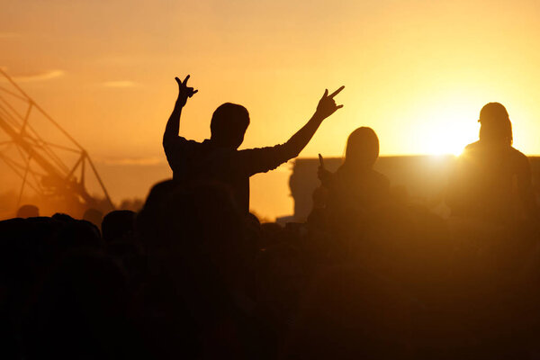 Silhouette Concert Person, Man on Shoulders in Crowd with hands up at summer Music Festival, sunset