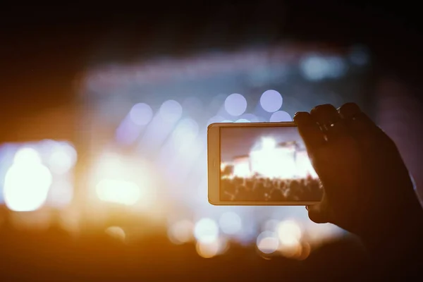 Mano con uno smartphone registra musica dal vivo festival e scattare foto del palco del concerto . — Foto Stock
