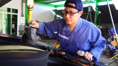 Mavi üniformalı tamirci oto tamirhanesinde yatıyor ve arabanın altında çalışıyor. Servis ve bakım aracı konsepti.