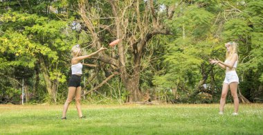 Kampüs bahçesinde frizbi oynayan iki güzel genç öğrenci.