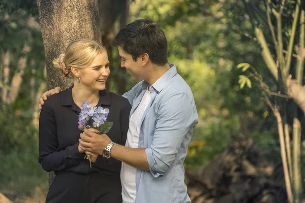 Happy young couple  Give flowers and walking together in park at summer. love and Valentines day concept.