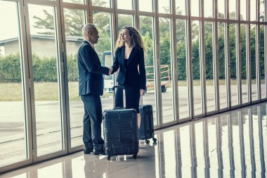 Başarılı iş adamları takım halinde yürüyor ve havaalanında el sıkışıyorlar., 