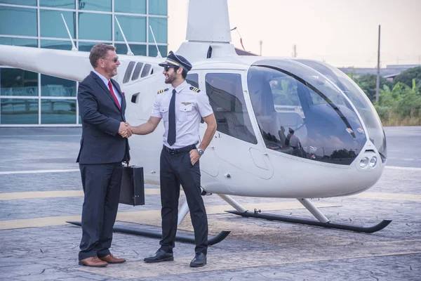 Kıdemli iş adamları, uçuş helikopterlerini güvenle hedeflerine ulaştırmak için kaptanla el ele tutuşuyor..