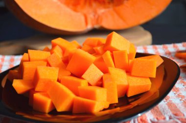 Doğranmış tahtada taze çiğ balkabağı. Gri-turuncu arka plan. Vejetaryen mutfağı.