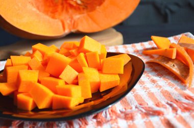 Doğranmış tahtada taze çiğ balkabağı. Gri-turuncu arka plan. Vejetaryen mutfağı.