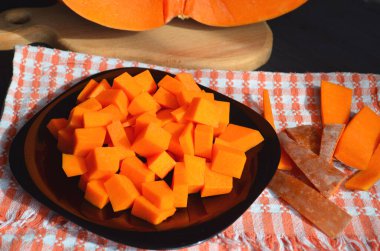 Doğranmış tahtada taze çiğ balkabağı. Gri-turuncu arka plan. Vejetaryen mutfağı.