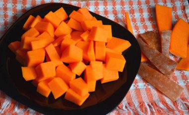 Doğranmış tahtada taze çiğ balkabağı. Gri-turuncu arka plan. Vejetaryen mutfağı.