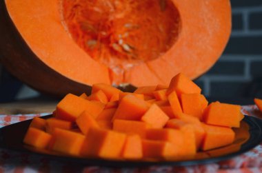 Doğranmış tahtada taze çiğ balkabağı. Gri-turuncu arka plan. Vejetaryen mutfağı.