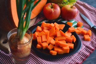 Doğranmış tahtada taze çiğ balkabağı. Gri-turuncu arka plan. Vejetaryen mutfağı.
