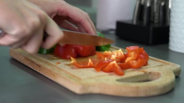 女の子は夕食を調理するためにボード上の赤と緑の新鮮なピーマンをカット — ストック動画