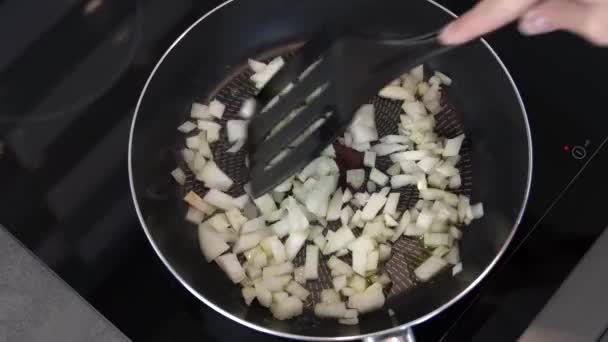 女の子は料理をしてるオリーブオイルのフライパンで玉ねぎを炒める — ストック動画