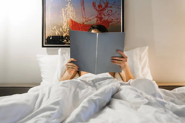 A man reads a magazine before going to bed in bed