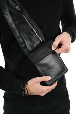 Bir adam omuzuna deri bir çanta geçirir ve görünüşünü duyurur.               