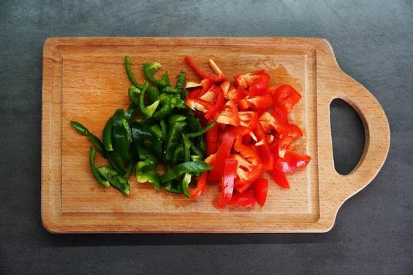 sweet fresh red and green peppers on a wooden board. cooking food. Slicing sweet pepper for salad.