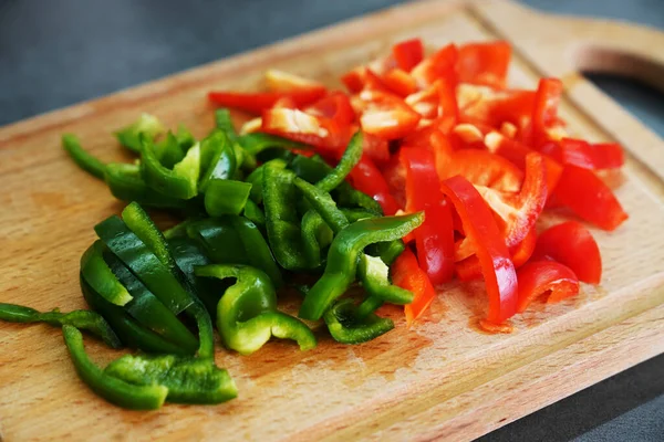 sweet fresh red and green peppers on a wooden board. cooking food. Slicing sweet pepper for salad.