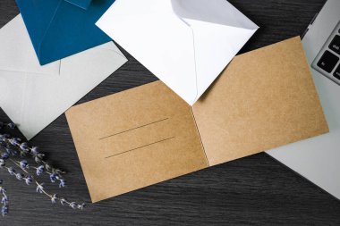 Masaüstünde zarflar olan kartpostallar. Karanlık bir masada dizüstü bilgisayarlı mektuplar.