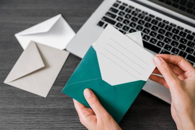 Masaüstünde zarflar olan kartpostallar. Karanlık bir masada dizüstü bilgisayarlı mektuplar.