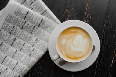 Masadaki bir kafede kapuçino. Sabah kahvesi ve gazete ayini..