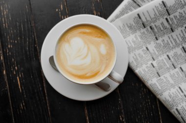 Masadaki bir kafede kapuçino. Sabah kahvesi ve gazete ayini..