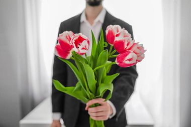Elinde bir buket çiçekle bir adam. Kutlama. Bir erkek lale verir..