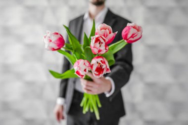 Elinde bir buket çiçekle bir adam. Kutlama. Bir erkek lale verir..