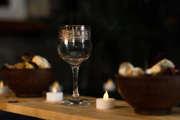 A relaxing evening with candles, wine and aromas. Glass goblet on the table. Rose petals. Romantic evening