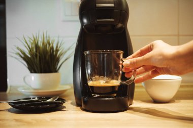 Kahve yapan kapsül. Espresso ile şeffaf bardak. Kız bir fincan alır.