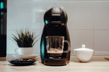 Kahve yapan kapsül. Espresso ile şeffaf bardak. Kız bir fincan alır.