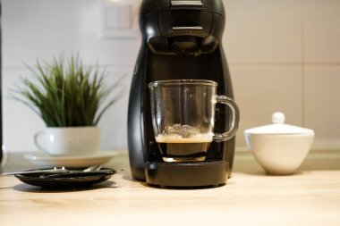 Kahve yapan kapsül. Espresso ile şeffaf bardak. Kız bir fincan alır.