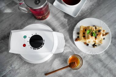 Krep ve çayın olduğu bir masada waffle ızgarası. panini presi