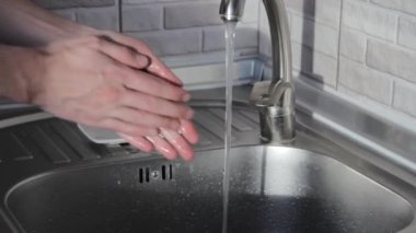 Bir adam evde ellerini yıkar. Koronavirüs ve bakterilerden kurtulmak için ellerinizi nasıl yıkayacağınızı.