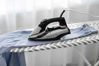 Katlanmış erkek gömlekleri ütü masasının yanında yatıyor..