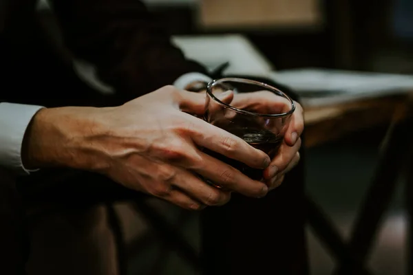 Adam güçlü bir alkollü içecek içiyor. Eller bardakta, yakın plan. kutlama
