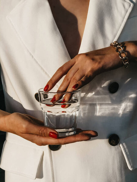 драгоценности в руках женщины. Девушка держит стакан воды. мода фото
