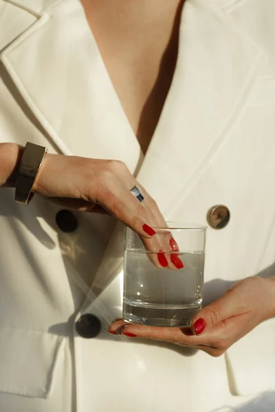 jewelry in the hands of a woman. girl holds a glass of water. fashion photo
