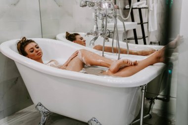 Kadın köpükle banyo yapıyor. Spa tedavileri. Zor bir günün ardından dinlenmek. Duşlu bir kadın