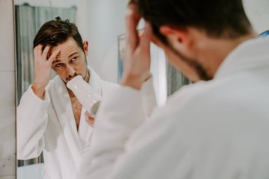 Beyaz önlüklü duştan sonra mutlu bir adam saçını kurutur. sabah spa tedavileri.