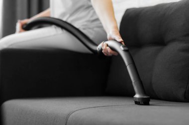 Kadın kanepeyi süpürüyor. Evin genel temizliği. Ev hanımı işleri yoluna koyuyor..