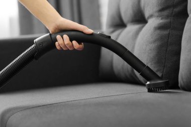 Kadın kanepeyi süpürüyor. Evin genel temizliği. Ev hanımı işleri yoluna koyuyor..