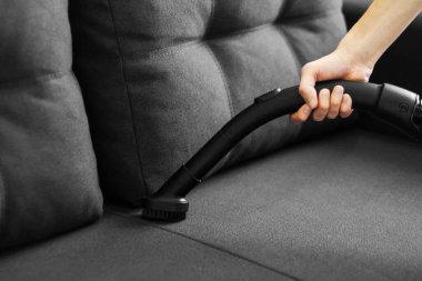 Kadın kanepeyi süpürüyor. Evin genel temizliği. Ev hanımı işleri yoluna koyuyor..