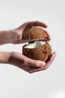 Kadın beyaz arka planda iki eliyle hindistan cevizi açıyor. sağlıklı yiyecekler.