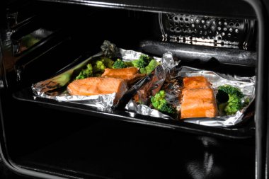 Mutfakta siyah konveksiyon fırını var. fırında somon.