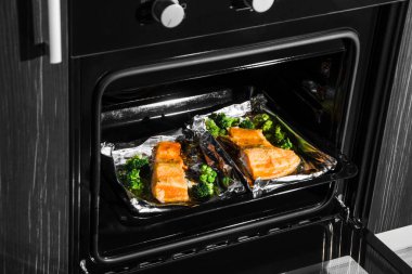 Mutfakta siyah konveksiyon fırını var. fırında somon.